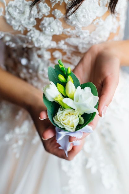 Primer del boutonniere con las rosas blancas. novia en vestido de novia