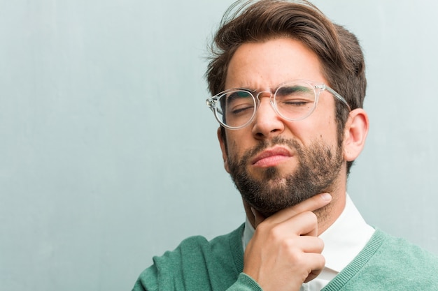 Primer de la cara del hombre del empresario hermoso joven con un dolor de garganta, enfermo debido a un virus