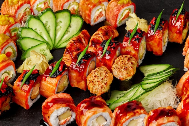 Primer conjunto de rollos, nigiri sushi y gunkan maki con salmón sobre fondo negro