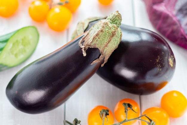 Primer conjunto de verduras frescas berenjena tomates pepinos y repollo rojo en la mesa de madera blanca