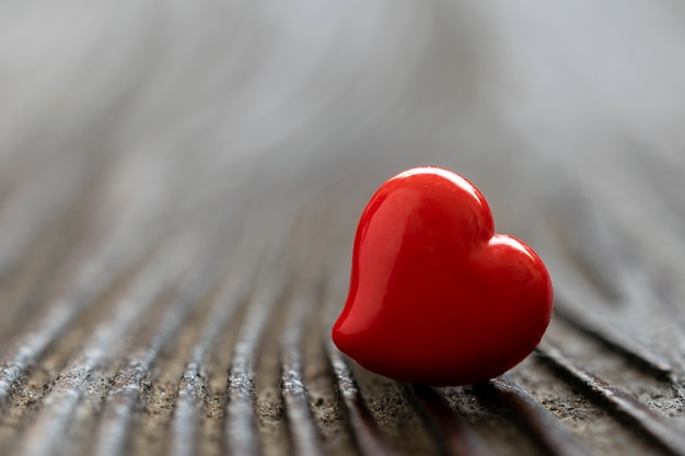 Primer del corazón rojo reflejado en la mesa de madera rústica. Día de San Valentín.