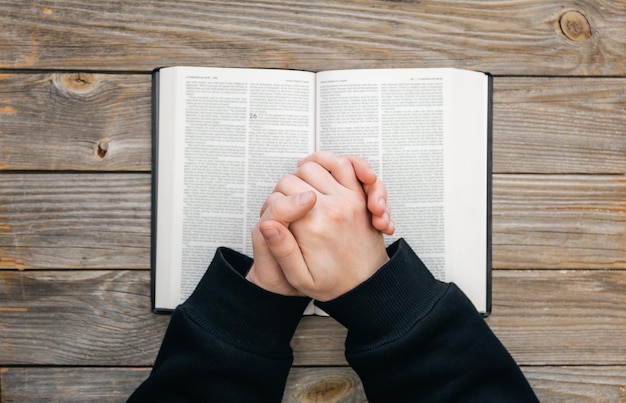 Foto primer cristiano leer biblia manos dobladas en oración en una santa biblia en la vista superior de fondo de madera