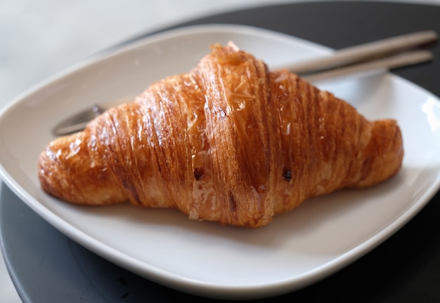 Primer croissant de mantequilla en un plato blanco