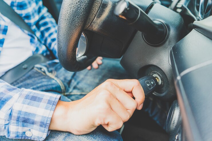 Primer dentro del coche de la llave que se sostiene masculina de la mano en la llave del motor del comienzo de ignición.