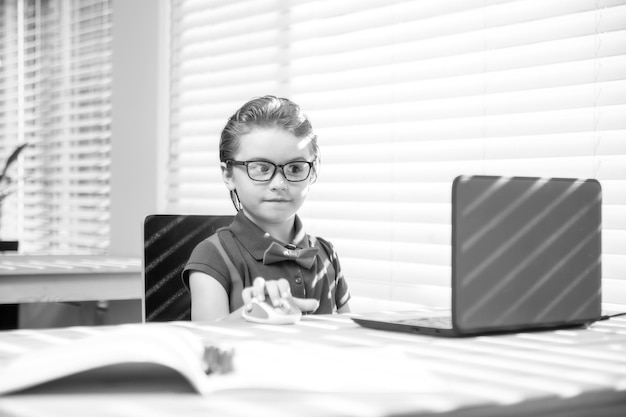 Primer día en el colegio. Un niño pequeño y lindo que usa una computadora portátil, estudia una computadora.