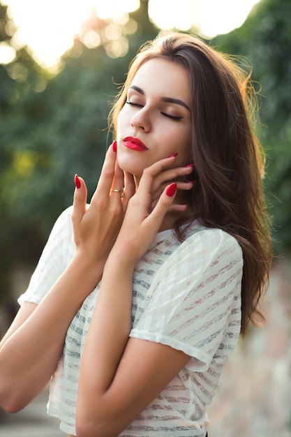 Primer disparo de modelo morena romántica con labios rojos posando con los ojos cerrados