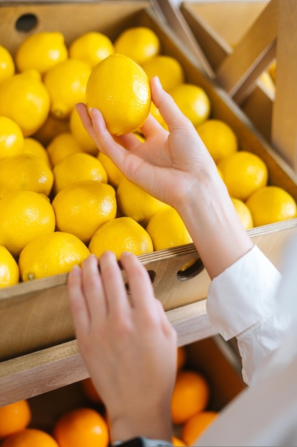 Primer disparo vertical de manos de irreconocible joven elegir limones en la tienda de comestibles