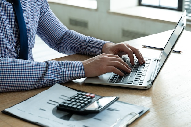 Foto primer empresario con calculadora y computadora portátil para calcular la investigación de impuestos financieros