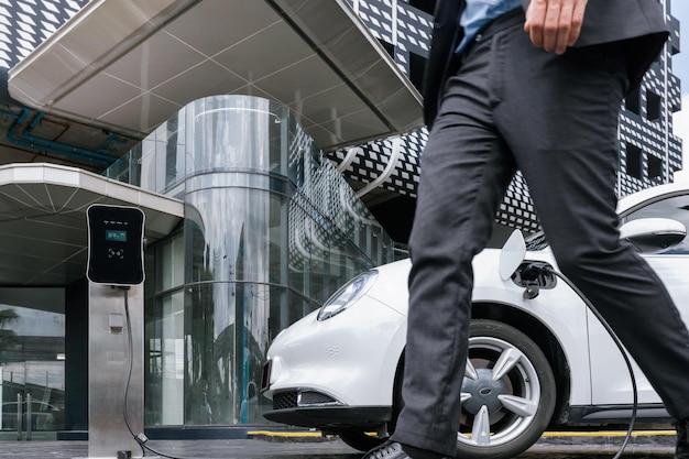 Primer empresario progresista con coche EV en la estación de carga pública