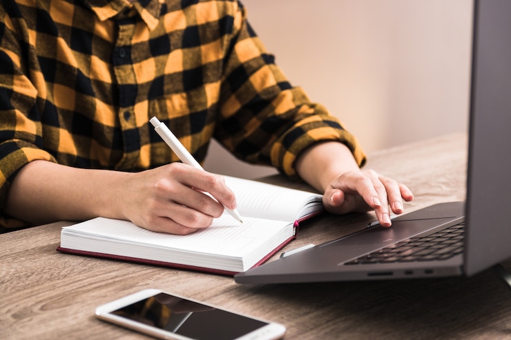 Foto primer estudiante toma el examen en línea a través de internet en la computadora portátil y toma notas. aprendizaje a distancia en crisis pandémica