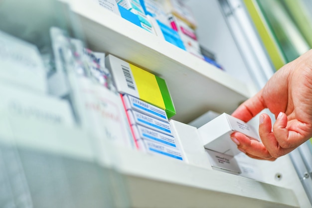 Primer farmacéutico mano sujetando la caja de la medicina en farmacia