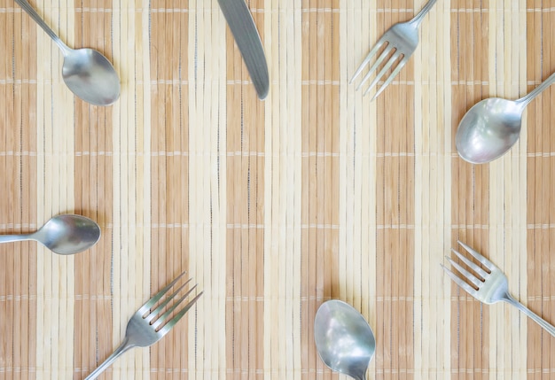 Primer grupo de cuchara y cuchillo de acero inoxidable en estera de madera con textura