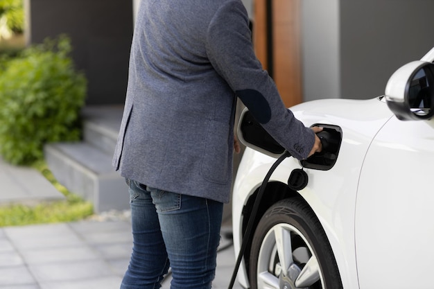 Primer hombre asiático progresista recarga su automóvil EV en la estación de carga doméstica