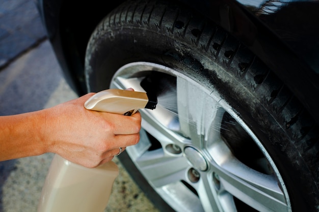 Primer hombre mano rociando una rueda de coche