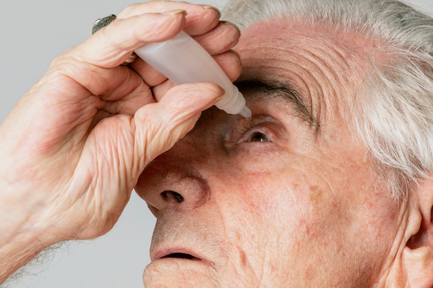 Primer hombre senior aplicando gotas para los ojos