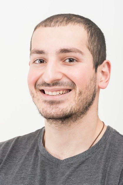 Foto primer del hombre sonriente joven en el fondo blanco