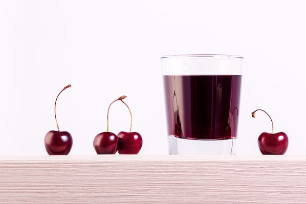 Primer del jugo fresco con las cerezas frescas en la tabla con el espacio de la copia.