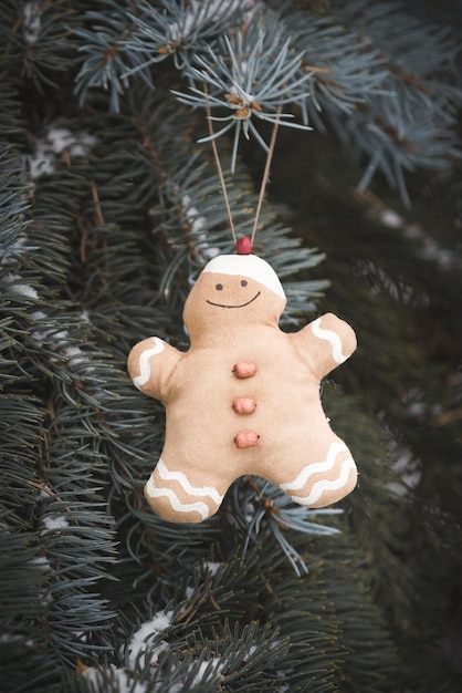 Foto primer juguete textil gingerbread man colgando de un árbol de navidad. fiesta