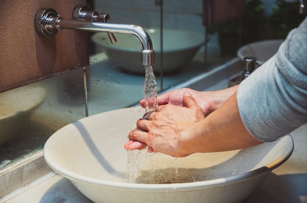Primer lavado de manos con grifo cromado y agua para la prevención de la pandemia de coronavirus