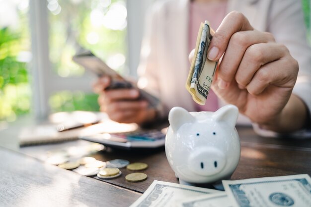 Foto primer de la mano de la mujer de negocios que pone el dinero en la batería guarra para ahorrar dinero. ahorro de dinero y concepto financiero