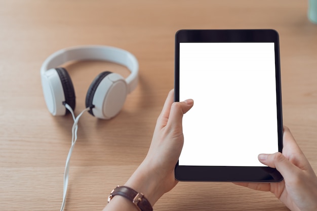 El primer de la mano de la mujer que sostiene la tableta digital en la tabla y la pantalla está en blanco.