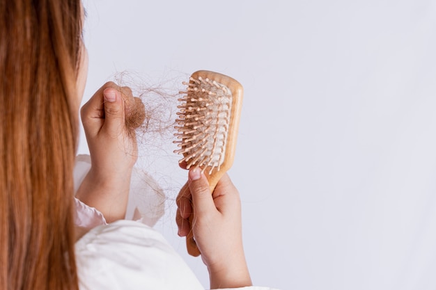 Primer mano que sostiene el peine y el problema de la caída del cabello aislado fondo gris.