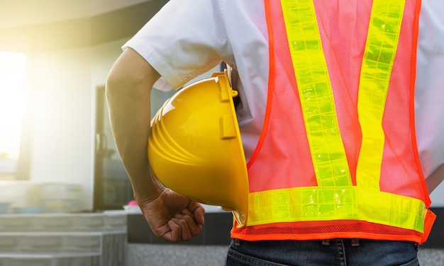 Primer mano sujetando el casco en el fondo de la construcción de viviendas