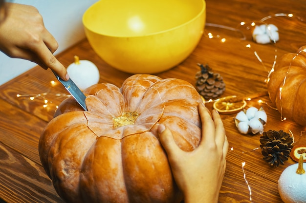 El primer de las manos del hombre talla la calabaza para Halloween en la tabla rústica de madera. Concepto de otoño