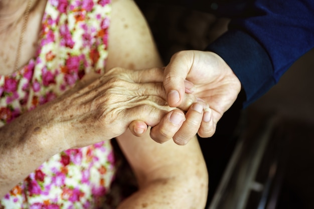 Primer, manos de una mujer mayor que lleva a cabo la mano de una mujer más joven. Concepto médico y sanitario.