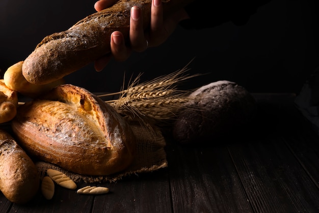 El primer de las manos de la mujer toma el pan fresco. Foto oscura