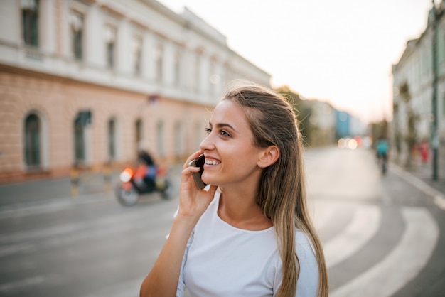 Primer de una muchacha hermosa que habla en el teléfono en la ciudad.