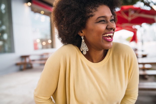 Primer de una mujer latina afroamericana hermosa que sonríe y que pasa tiempo agradable en la cafetería.