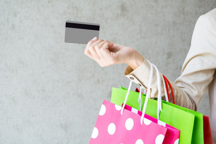 Primer de la mujer que sostiene bolsos de compras y que usa una tarjeta de crédito.