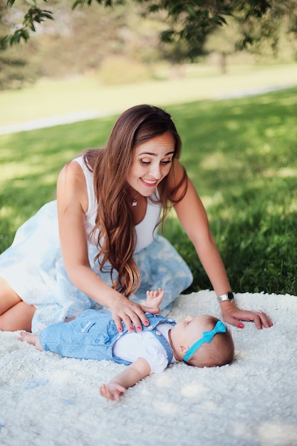 Primer de la mujer sonriente hermosa que juega con su bebé lindo en vestido azul.