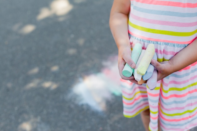 Primer del niño que sostiene la tiza coloreada para dibujar.