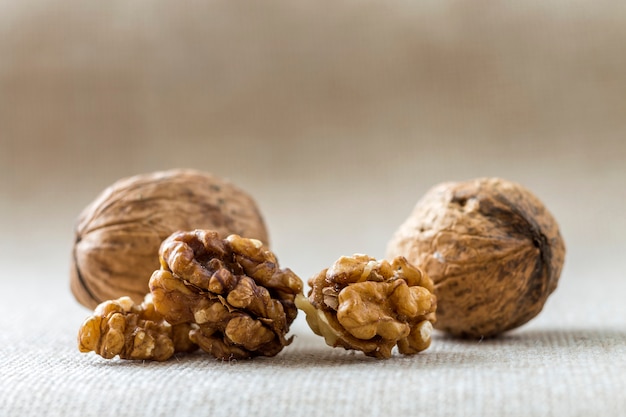 Primer de nueces, en cáscara de madera y granos aislados en fondo del espacio de la copia ligera. Concepto de comida orgánica saludable.