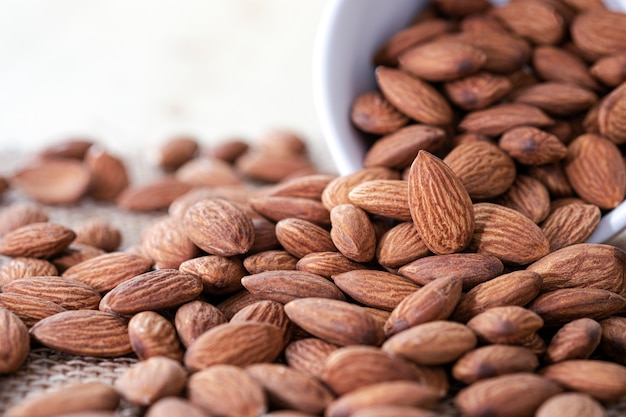 El primer de la nuez de las almendras en el tazón de fuente blanco se vertió en los sacos. La nuez de almendra es una nutrición popular y alta en proteínas.