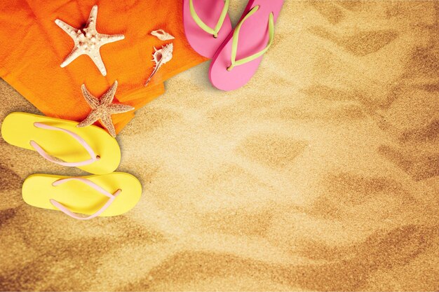 Primer plano de accesorios de playa en la arena. Chanclas, gafas de sol, estrellas de mar, toalla