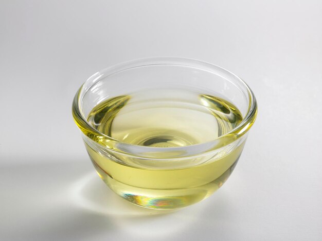 Primer plano de aceite en un cuenco de vidrio contra un fondo blanco