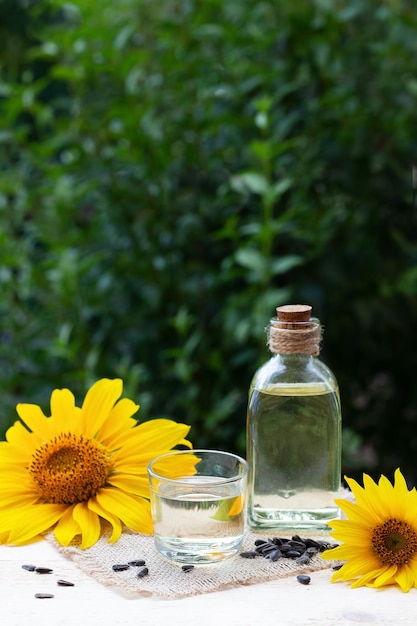 Primer plano de aceite de girasol en un vaso de botella con semillas y girasol