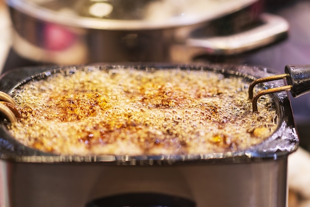 Primer plano de aceite hirviendo burbujeante caliente para freír el fondo, el mercado tailandés de comida callejera