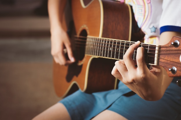 primer plano de adolescente, niña, mujer tocando la guitarra con feliz.