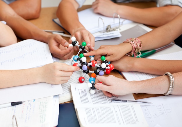 Primer plano de adolescentes estudiando moléculas en una biblioteca