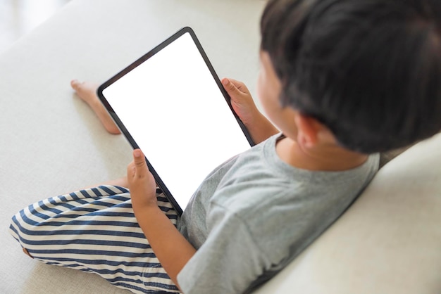 Primer plano adorable feliz asiático niño mano uso dedo toca con tableta digital pantalla blanca aislada sobre fondo blanco Concepto de tecnología conexión comunicación social