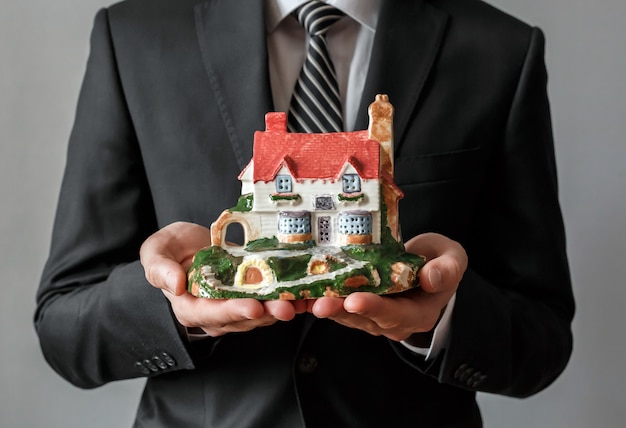 Primer plano de un agente inmobiliario con una casa en la mano. Negocio inmobiliario.
