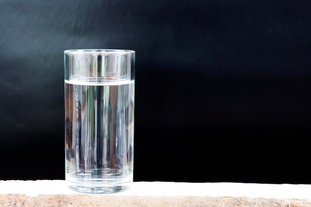 Primer plano de agua en un vaso sobre una mesa contra un fondo negro