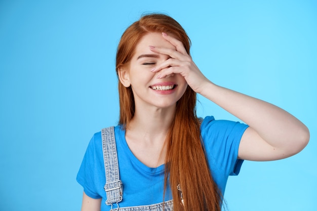 Primer plano, alegre, entusiasta, mujer europea, reír, despreocupado, disfrute, verano, libre, relajante, fines de semana, cerrar, ojos, sostener la mano, cara, alegre, sonriente, ampliamente, sol, playa, stand, fondo azul