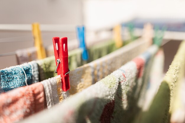 Primer plano de alfileres de colores y colgar la ropa o paños de cocina. Pinzas de plástico de colores en un tendedero. Pin rojo Tareas del hogar. Deberes. Lavandería. Lava la ropa.