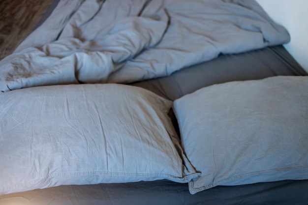 Foto primer plano de almohadas y mantas grises con una sábana en la cama