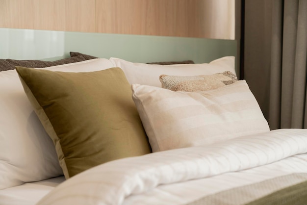 Primer plano de almohadas suaves de color beige blanco en la cama y el diseño de interiores del dormitorio de la manta concepto de ideas de lujo de mucama de cama